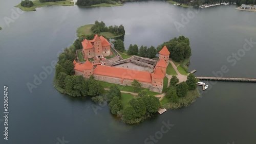 Aerial shot of the Trakai castle surrounded by trees over the Galves lake in Trakai, Lithuania photo