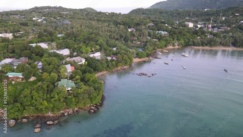 Drone aerial move backwards over tropical blue water with green mountainside houses in Thailand Drone aerial move backwards over tropical blue water with green mountainside houses in Thailand