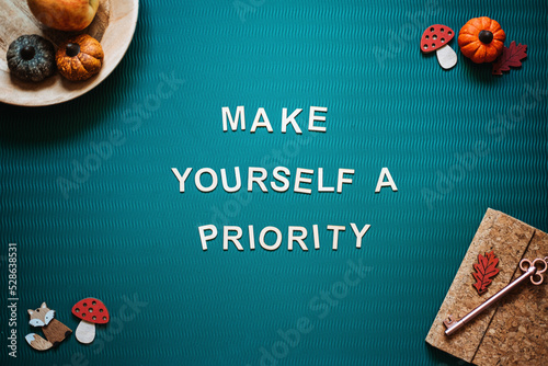 Photos Self-care quotes, make yourself a priority words on green background flat lay