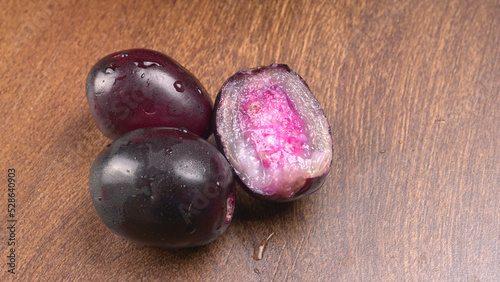 Jambul or Jamun (Syzygium cumini) in yellow bowl isolated on textured background.