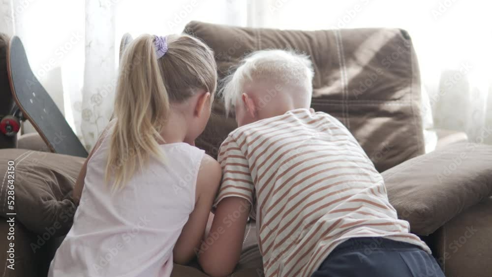 Close-up, back view, children playing gadgets at home. Close-up, back view, children playing gadgets at home.