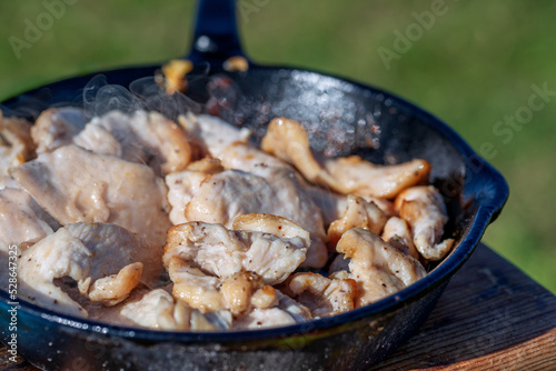Fried chicken fillet in a cast iron skillet. Outdoor cooking.