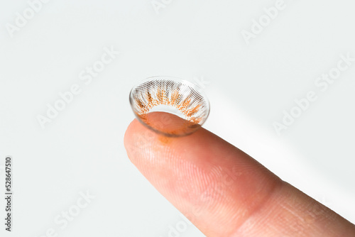 Finger of woman holding with contact lens.