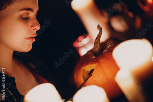 Young woman making Halloween pumpkin Jack-o-lantern with candles. Female hands cutting pumpkins with knife