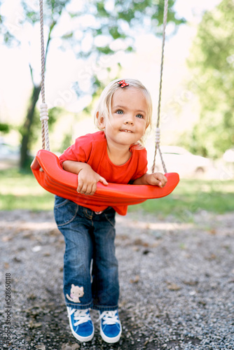 Little girl lay on her stomach on a swing in the park. High quality photo photo