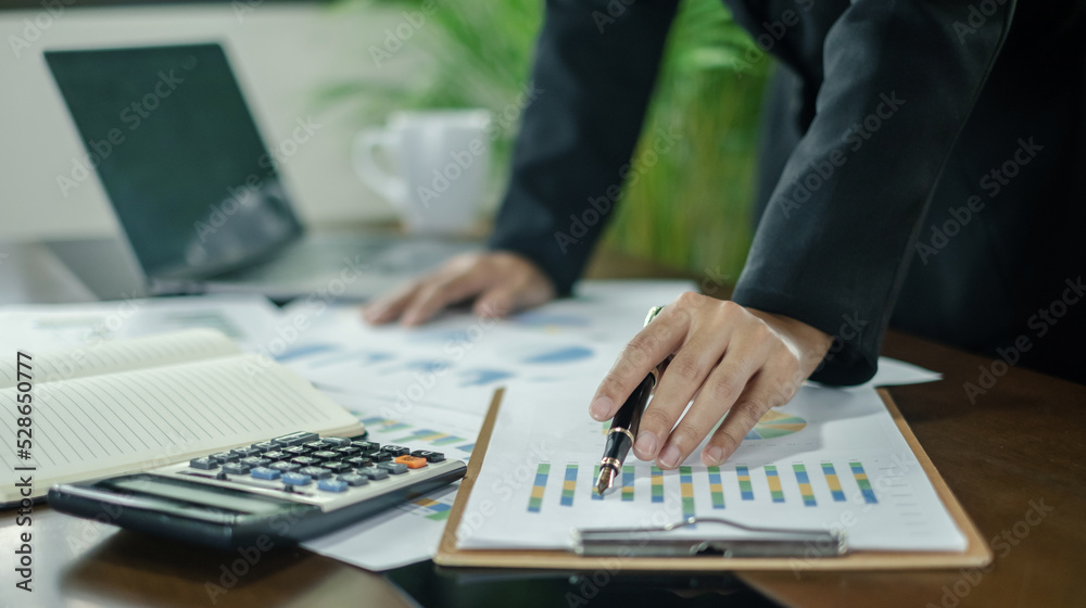 Asian female accountants sit at their desks and calculate financial graphs showing results about their investments, planning a successful business growth process Asian female accountants sit at their desks and calculate financial graphs showing results about their investments, planning a successful business growth process
