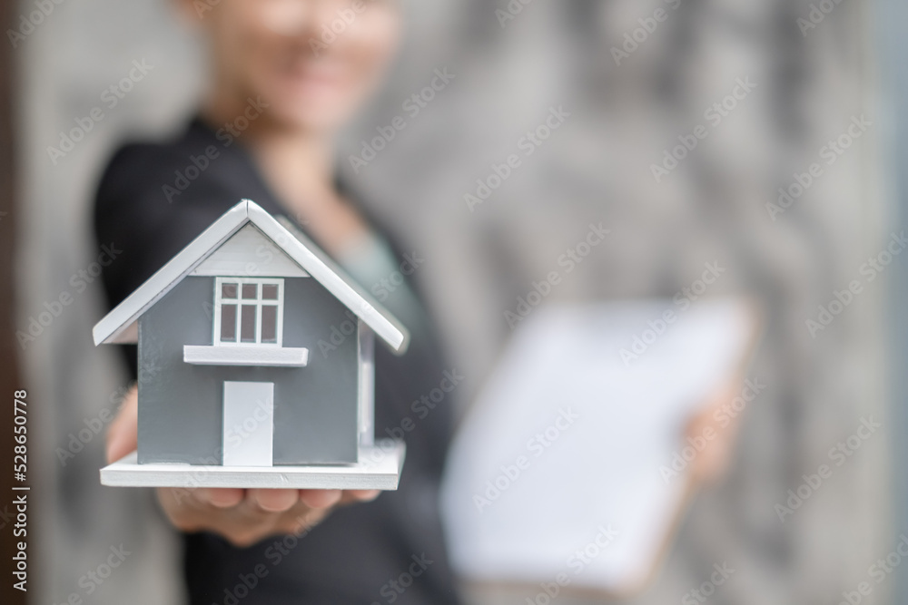 Home insurance concept and real estate. Businesswoman holding a house model working in investment about renting a house, buying a house, and home insurance Home insurance concept and real estate. Businesswoman holding a house model working in investment about renting a house, buying a house, and home insurance