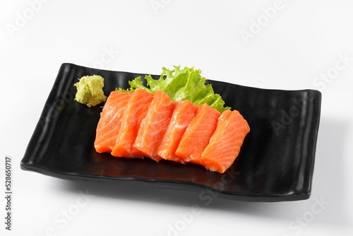 Salmon Sashimi Arranged in a black plate with wasabi on the side. on a white background Japanese food menu