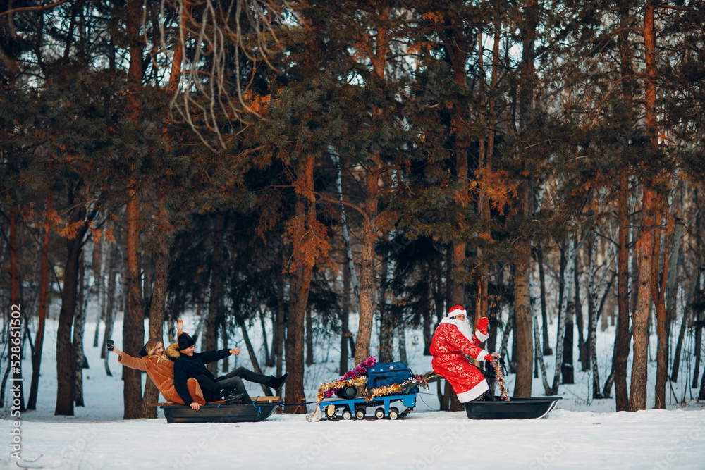 Santa claus riding snowmobile couple in love in the winter forest.
