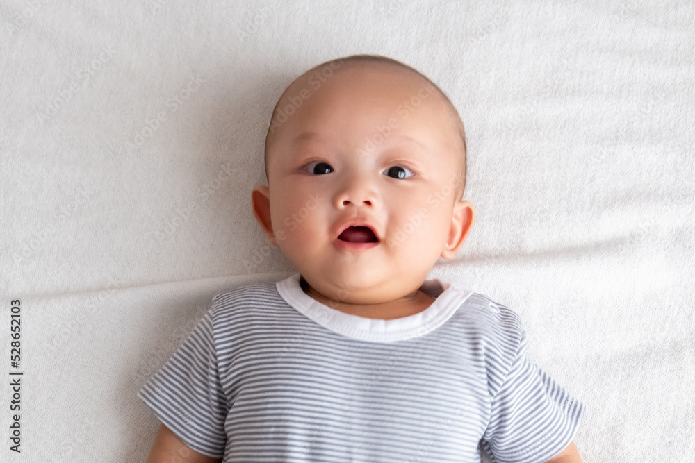 baby boy with big eyes smiling with mouth open on the white mattress baby boy with big eyes smiling with mouth open on the white mattress