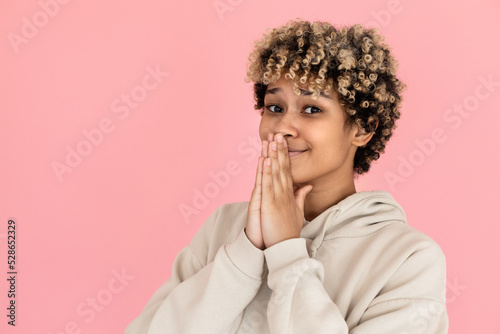 Woman making pleading gesture. Female model in hoodie with curly hair looking up. Portrait  studio shot concept