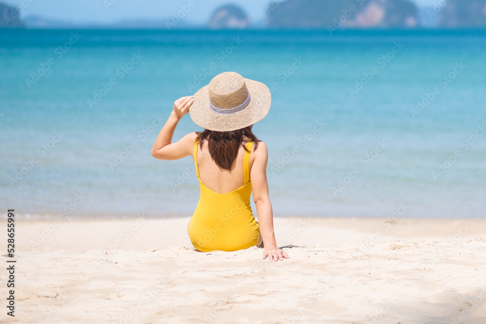 Woman tourist in yellow swimsuit and hat, happy traveler sunbathing at Paradise beach on Islands. destination, wanderlust, Asia Travel, tropical summer, vacation and holiday concept Woman tourist in yellow swimsuit and hat, happy traveler sunbathing at Paradise beach on Islands. destination, wanderlust, Asia Travel, tropical summer, vacation and holiday concept