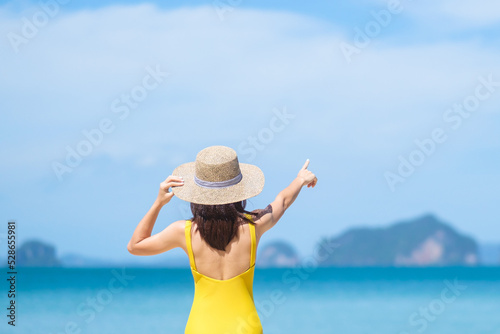 Woman tourist in yellow swimsuit and hat, happy traveler sunbathing at Paradise beach on Islands. destination, wanderlust, Asia Travel, tropical summer, vacation and holiday concept