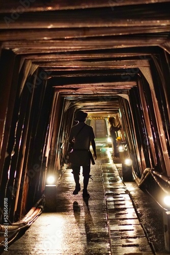 A lonely man walking in a tunnel.