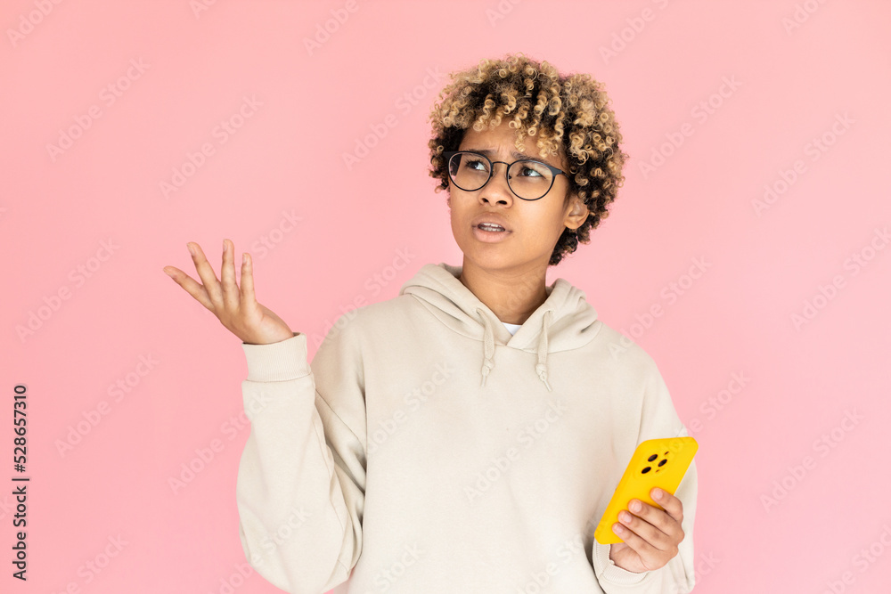 Portrait of bewildered African American woman with phone. Female model in glasses with curly hair looking up. Portrait, studio shot, emotion concept