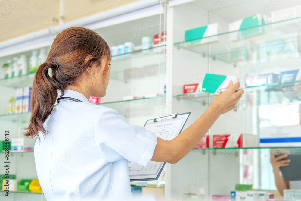 Young asian pharmacist checking the shelves  at the pharmacy
