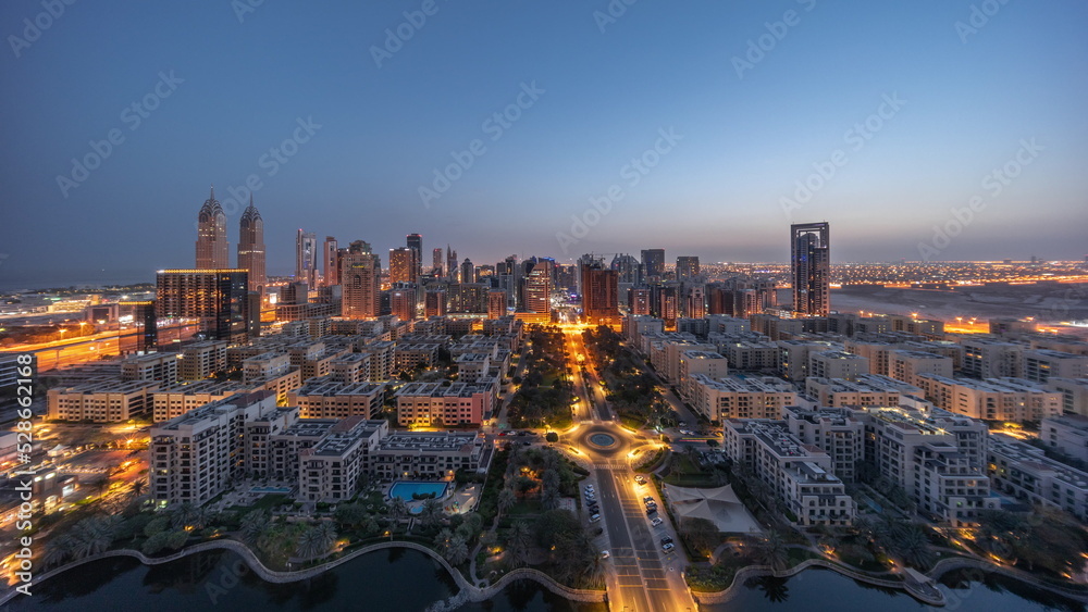 Obraz premium Panorama of skyscrapers in Barsha Heights district and low rise buildings in Greens district aerial night to day timelapse.