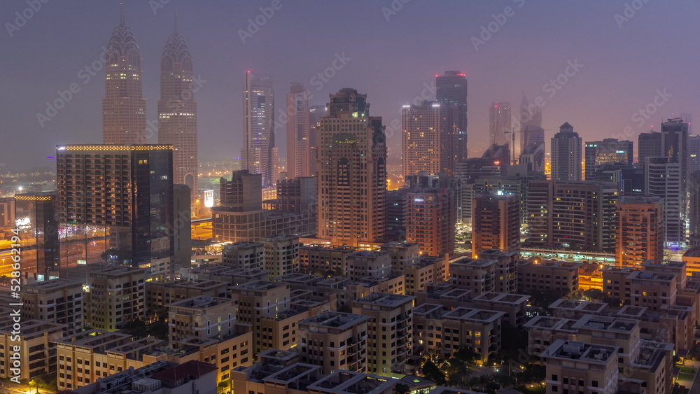 Skyscrapers in Barsha Heights district and low rise buildings in Greens district aerial night to day timelapse.