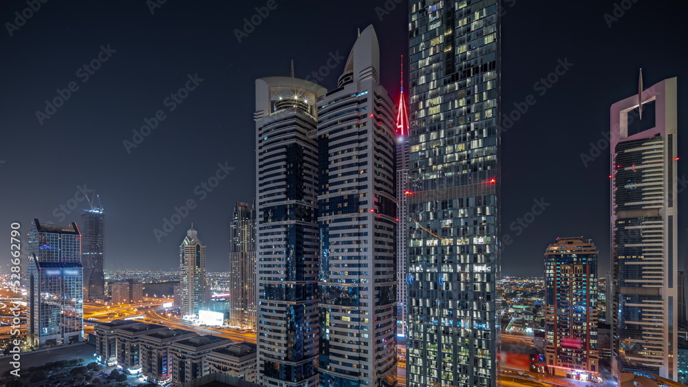 Obraz premium Panorama showing aerial view of Dubai International Financial District with many skyscrapers night timelapse.