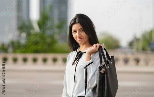 Obraz na plátně The young businesswoman of Indian origin begins her work in the city with a briefcase, full of energy and security