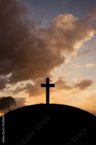 Cross religion symbol shape over sunset sky 