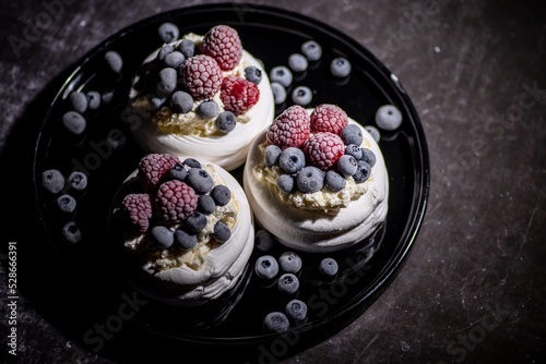 Fototapeta Delicious mini pavlova meringue desserts served with frozen frosty berries and m