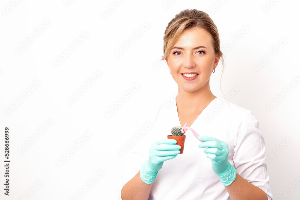 A smiling female beautician holds little green cactus with the razor in her hands. Hair removal concept A smiling female beautician holds little green cactus with the razor in her hands. Hair removal concept