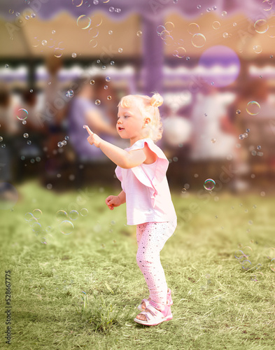 Little girl blows soap bubbles in the sun.