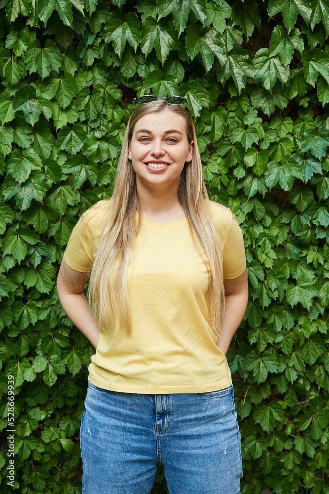 portrait of a young woman in sunglasses on her head, smiling, looking at the camera against the background of green foliage in summer portrait of a young woman in sunglasses on her head, smiling, looking at the camera against the background of green foliage in summer