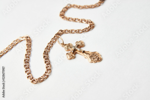 Gold chain with golden cross pendant on white background