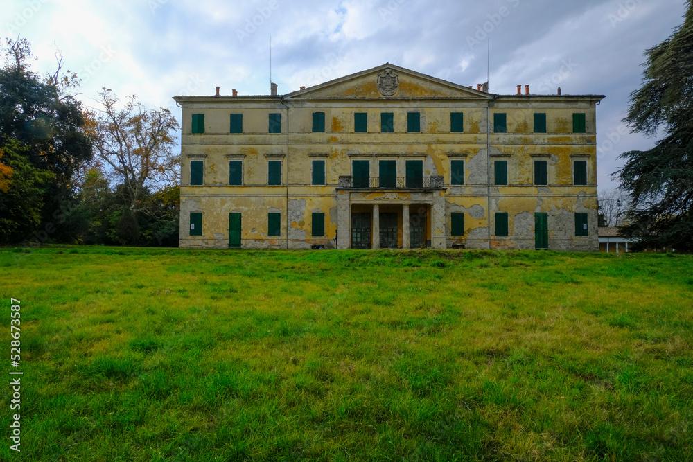 Yellow facade of the Villa Casino dei Boschi across the green meadow and dramatic sky. Boschi di Carrega, Emilia-Romagna, Italy