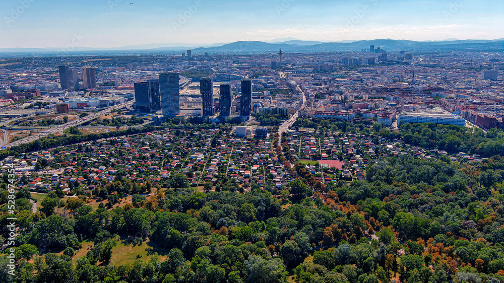 Vienna downtown district and urban skyline aerial view in Austria. Flying above green nature ft. suburban residential neighborhood.