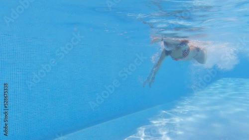 underwater image of a beautiful athletic young woman swimming the crawl and doing a U-turn