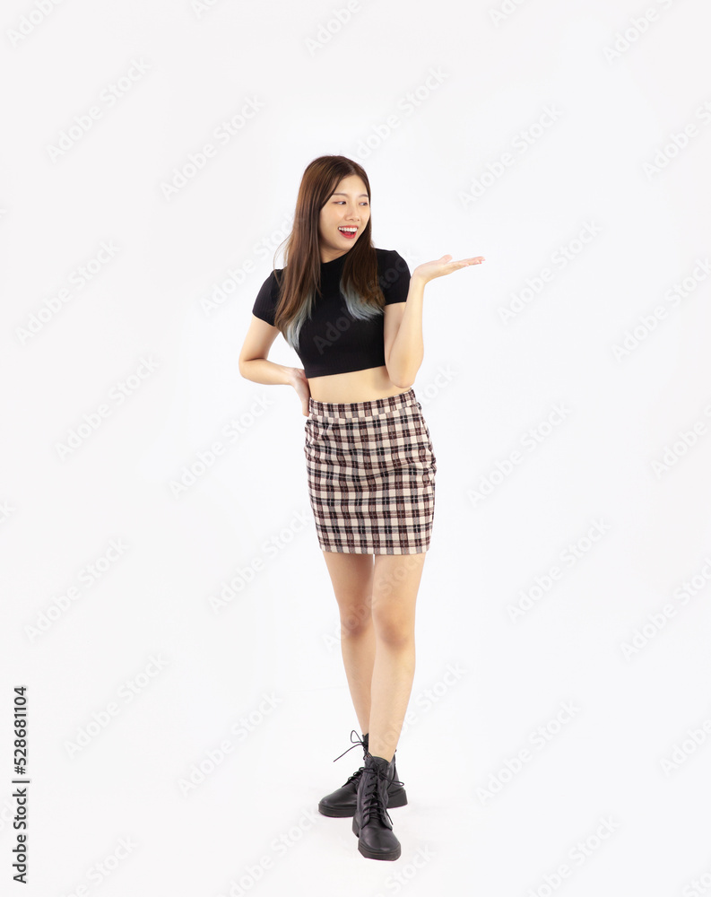 Young asian woman long hair in black crop t shirt and skirt with ankle boots posing standing and pointing on white background. Full body model. Young asian woman long hair in black crop t shirt and skirt with ankle boots posing standing and pointing on white background. Full body model.