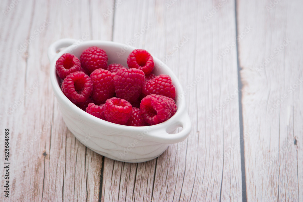 Harvest of Fresh ripe farm raspberry on the table, on wooden background in white plate. Top view, copy space. Flat lay with space for text. Harvest of Fresh ripe farm raspberry on the table, on wooden background in white plate. Top view, copy space. Flat lay with space for text.