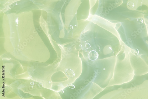 The texture of a green gel or serum with hyaluronic acid for the face. Cosmetic transparent liquid cream with oxygen bubbles. Wellness and beauty concept. Sanitizer, virus protection.