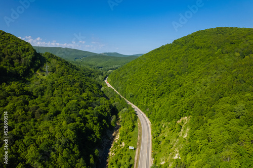 Aerial view of winding road from the high mountain pass. Great road trip trough the dense woods. Birds eye view. © Quatrox Production