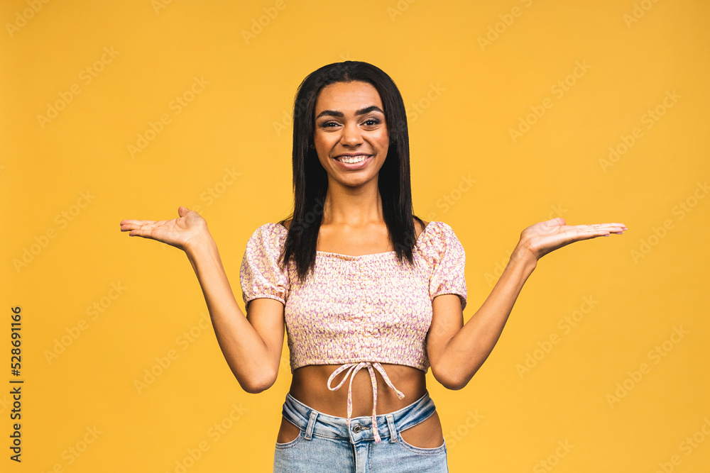 Business Concept - Portrait of beautiful african american black young presenting by pointing hand on side isolated over yellow background. Business Concept - Portrait of beautiful african american black young presenting by pointing hand on side isolated over yellow background.