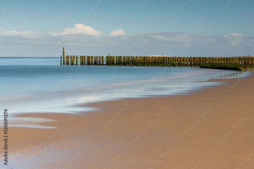 A sandy beach at the North sea in the Netherlands seen from the beach in Zoutelande in Zeeland with the typical wooden breakers for the waves during high water