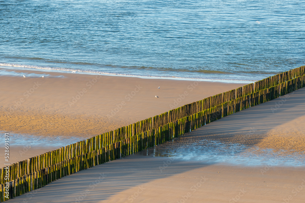 A sandy beach at the North sea in the Netherlands seen from the beach in Zoutelande in Zeeland with the typical wooden breakers for the waves during high water