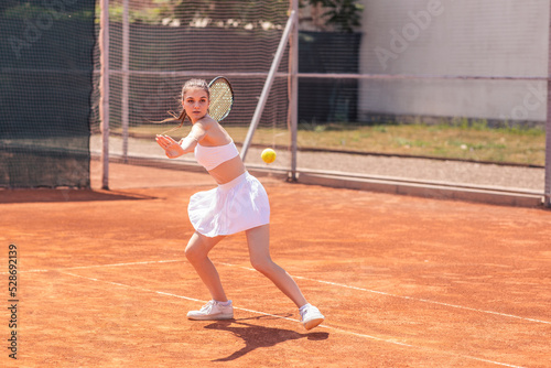 Good looking young woman professional tennis player hitting the ball hard outdoor on the tennis court she wearing uniform concept of healthy lifestyle and professional sport © spoialabrothers