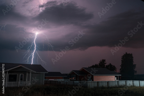 Thunderbolt over the house in the village and dark stormy sky on the background