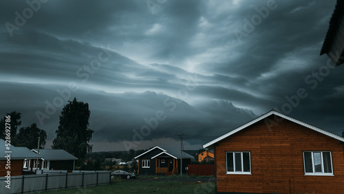 Thunderbolt over the house in the village and dark stormy sky on the background