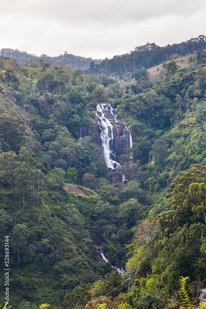 Grandiose unusually beautiful waterfall in the green jungle of the island of Sri Lanka. Overall plan. Ella. Vertical frame