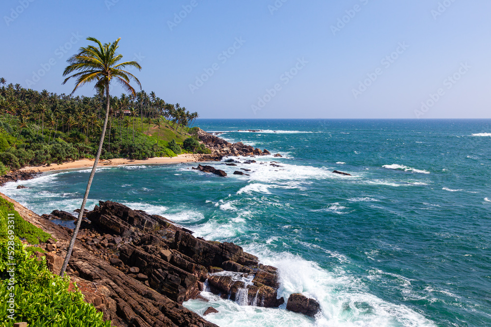Turquoise waves crash on the sandy shore of the Indian Ocean. Mirissa. Overall plan