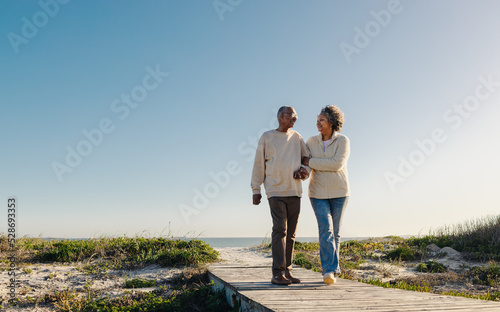 Fototapete Romantic senior couple walking down a foot bridge at the beach