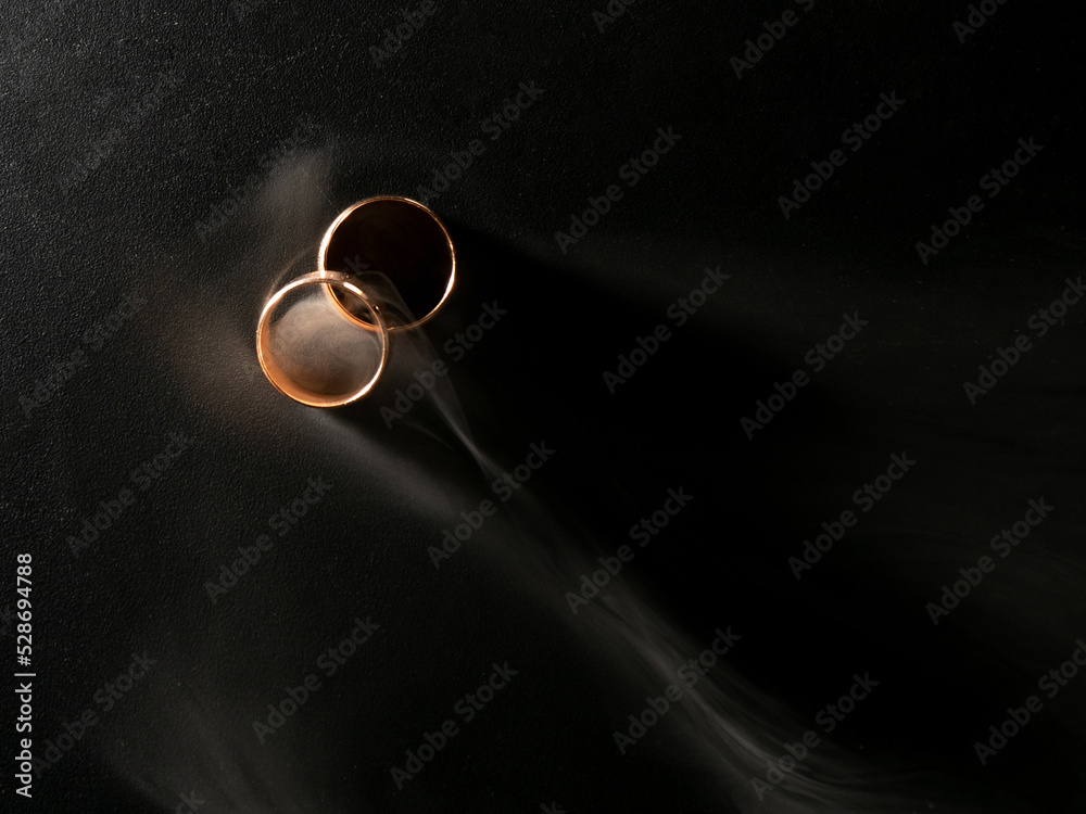 Gold wedding rings with smoke on black background