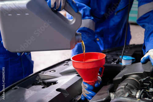 Canvas Print Closeup hands of mechanic man pouring motor oil in engine car in the garage, automobile change lubricant or diesel, worker refilling fluid at auto service, one person, vehicle and transportation