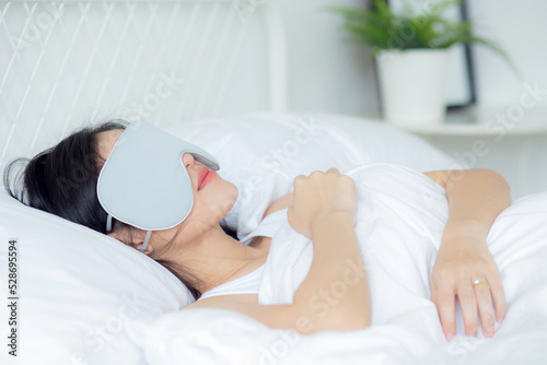 Beautiful young asian woman wearing cover eye and sleeping on bed with head on pillow comfort and happiness in the bedroom at home, girl with relax and leisure for wellness, lifestyles concept.