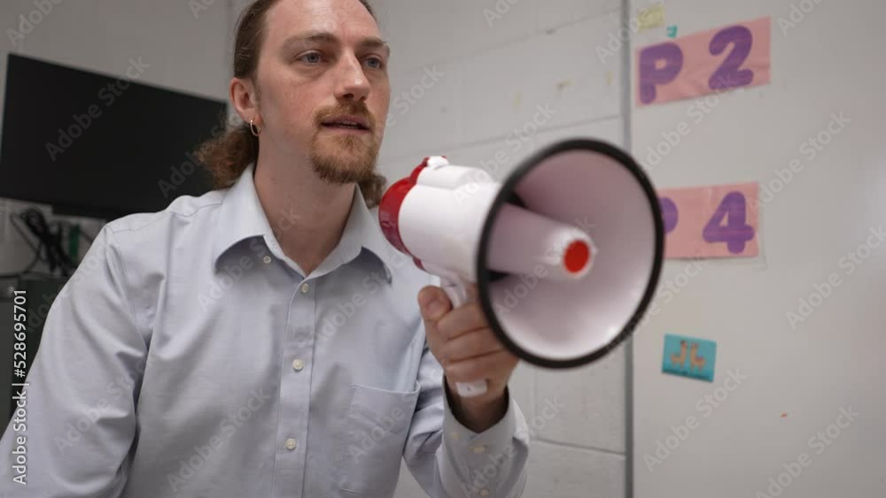 Angry teacher shouting in classroom into megaphone loudhailer, bullhorn, trying to make students listen. Concept of teacher frustration with class. Angry teacher shouting in classroom into megaphone loudhailer, bullhorn, trying to make students listen. Concept of teacher frustration with class.